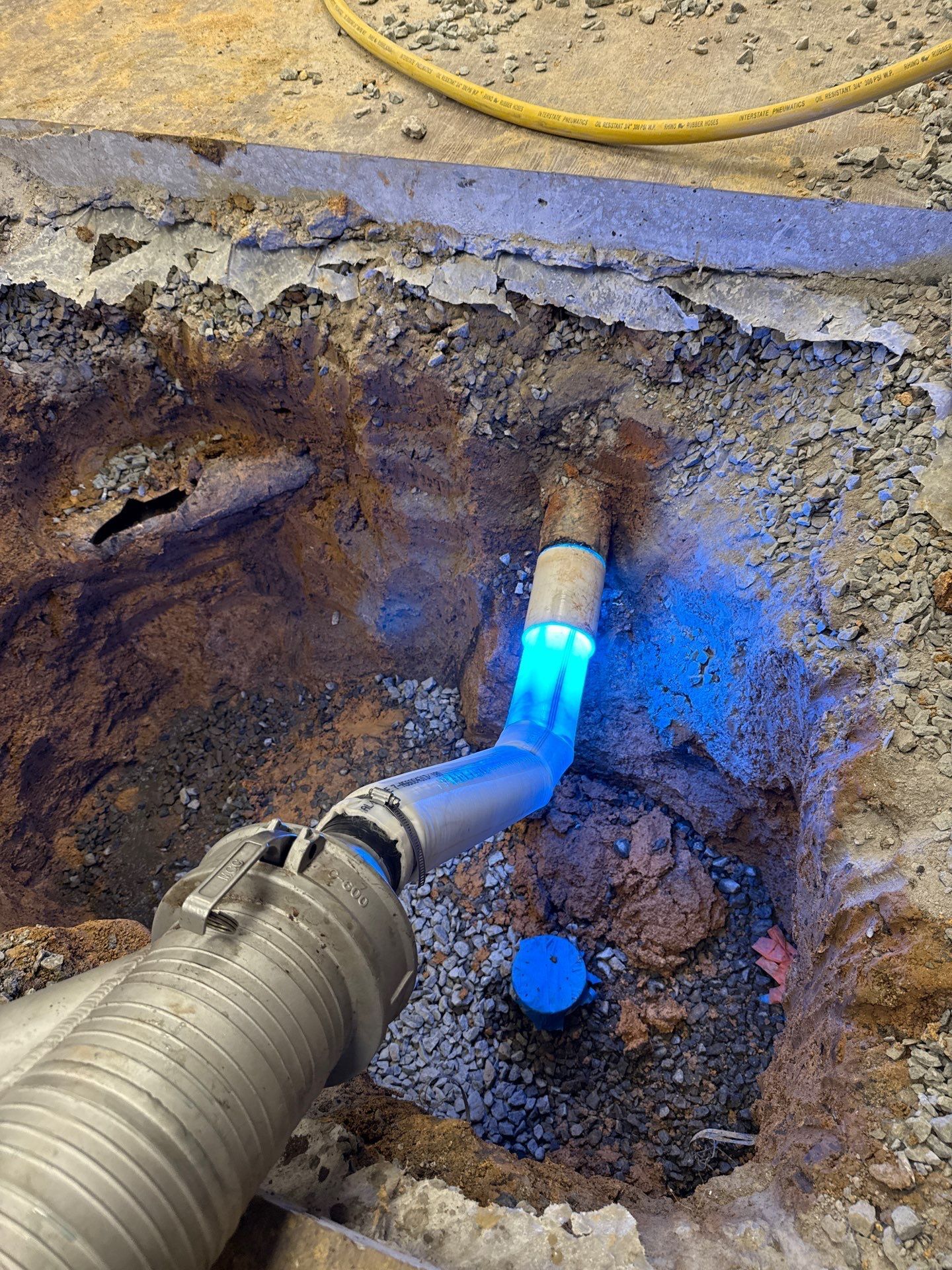 Cured-in-place pipe liner glowing blue during UV curing inside a repaired sewer joint