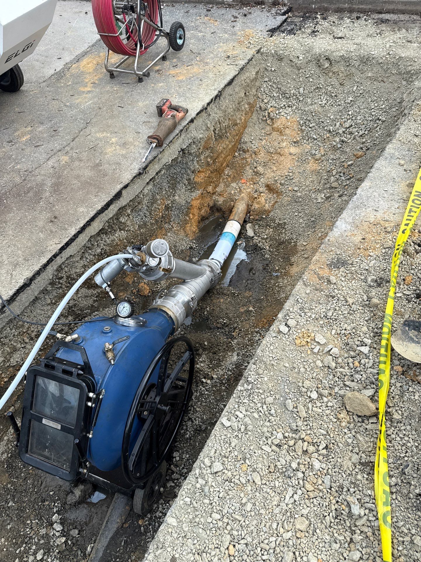 Excavated access trench with CIPP lining equipment during a trenchless sewer repair