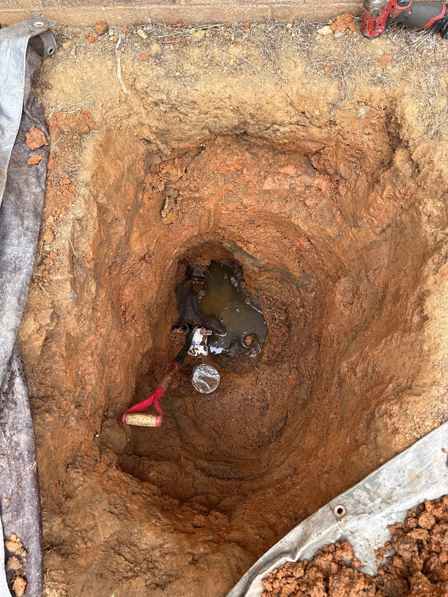 Excavated sewer line showing a collapsed drain with standing water
