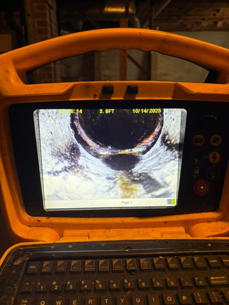 Sewer camera footage showing water standing in the bottom of a sewer pipe near a joint