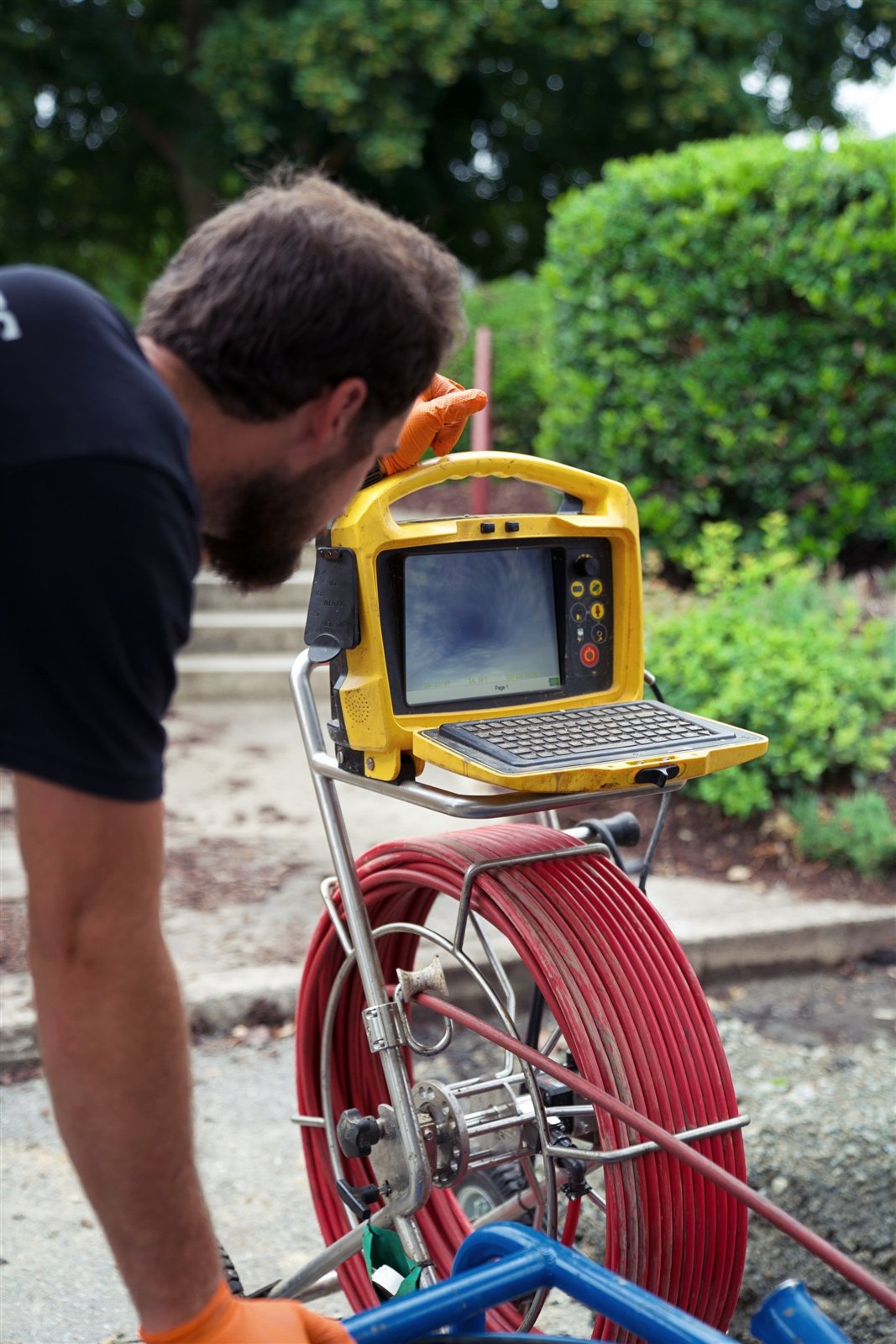 Technician reviewing live sewer camera inspection footage on a monitor mounted on the camera reel