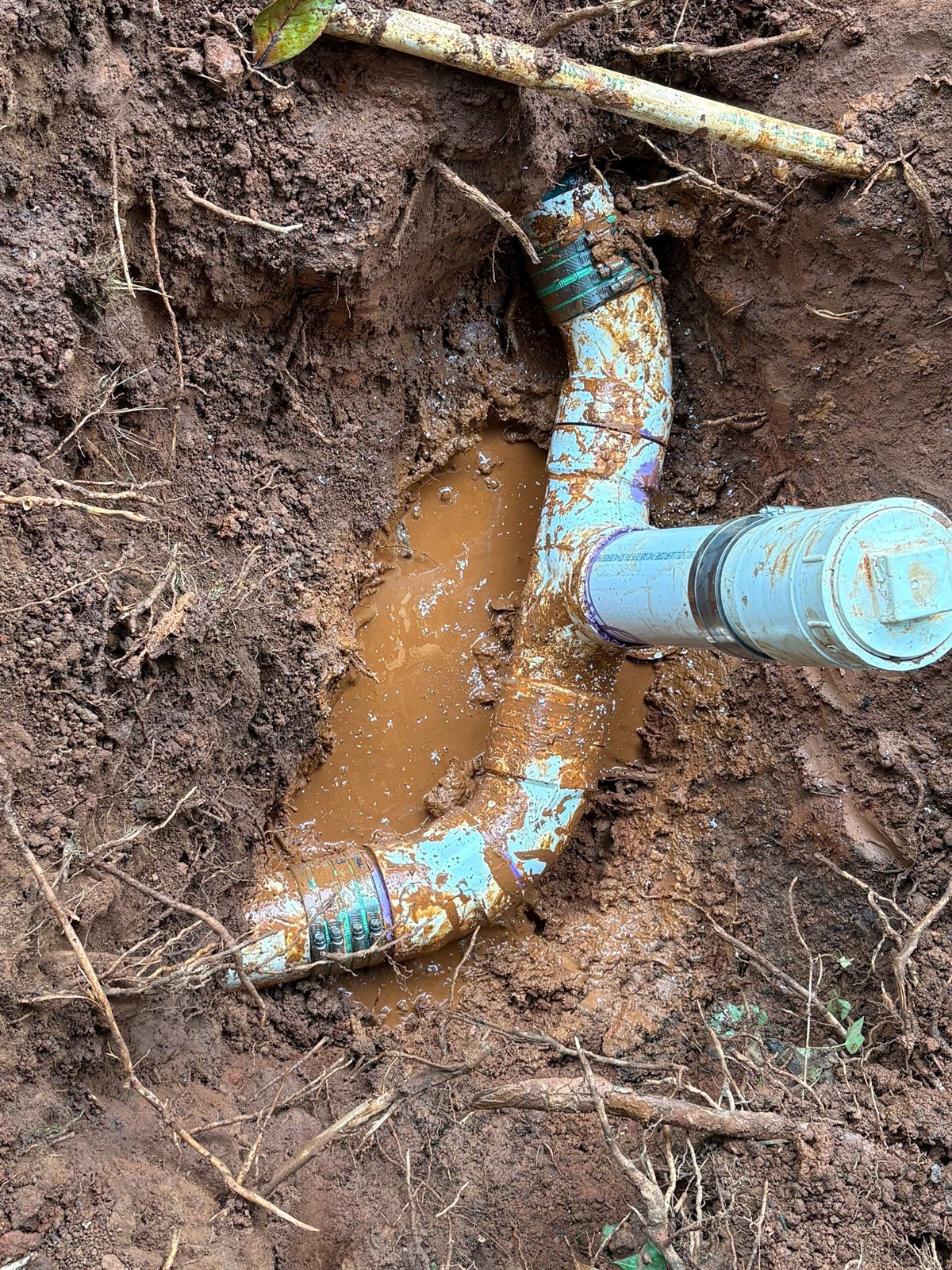 A broken underground sewer pipe exposed during repair, the kind of defect that lets sewer odor escape around a property.