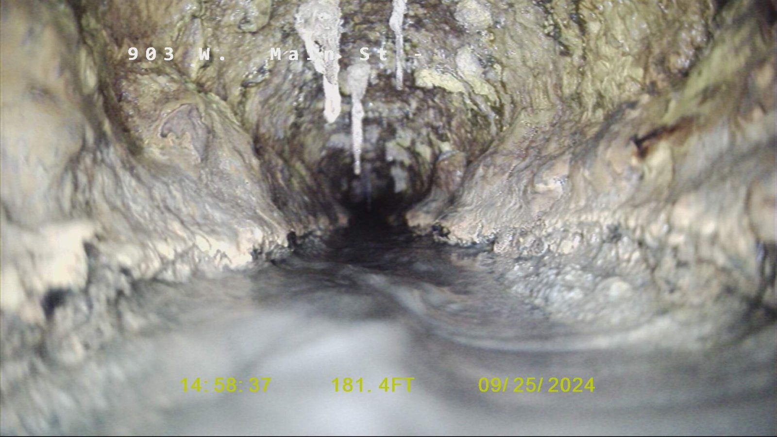 Camera inspection of a sewer line showing scale buildup and obstruction.