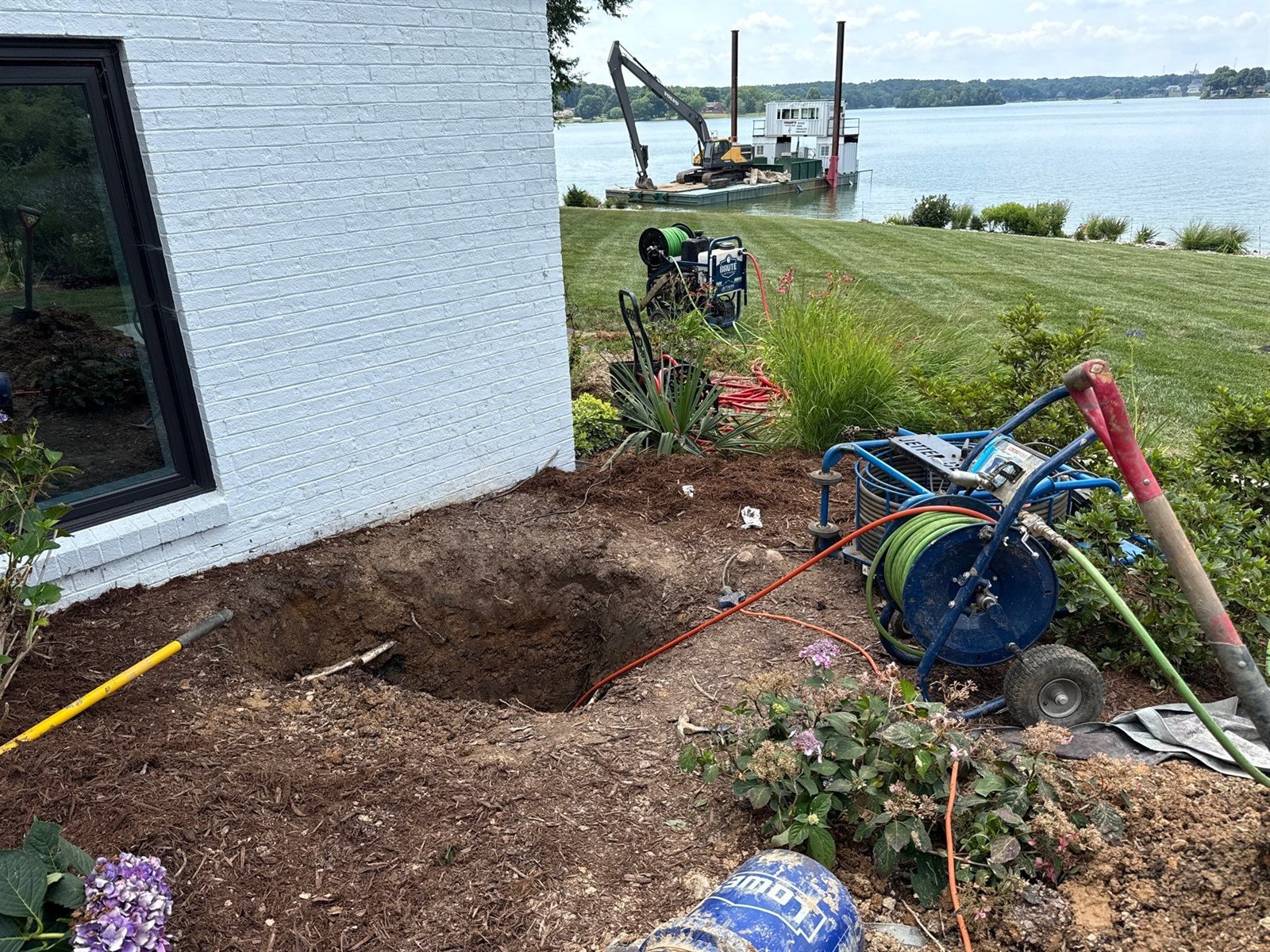 Excavated access pit exposing the sewer pipe at a residential property before trenchless pipe bursting.