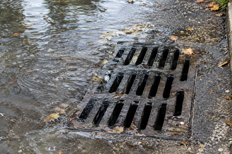Commercial storm drain inlet showing overflow indicators from restricted capacity.