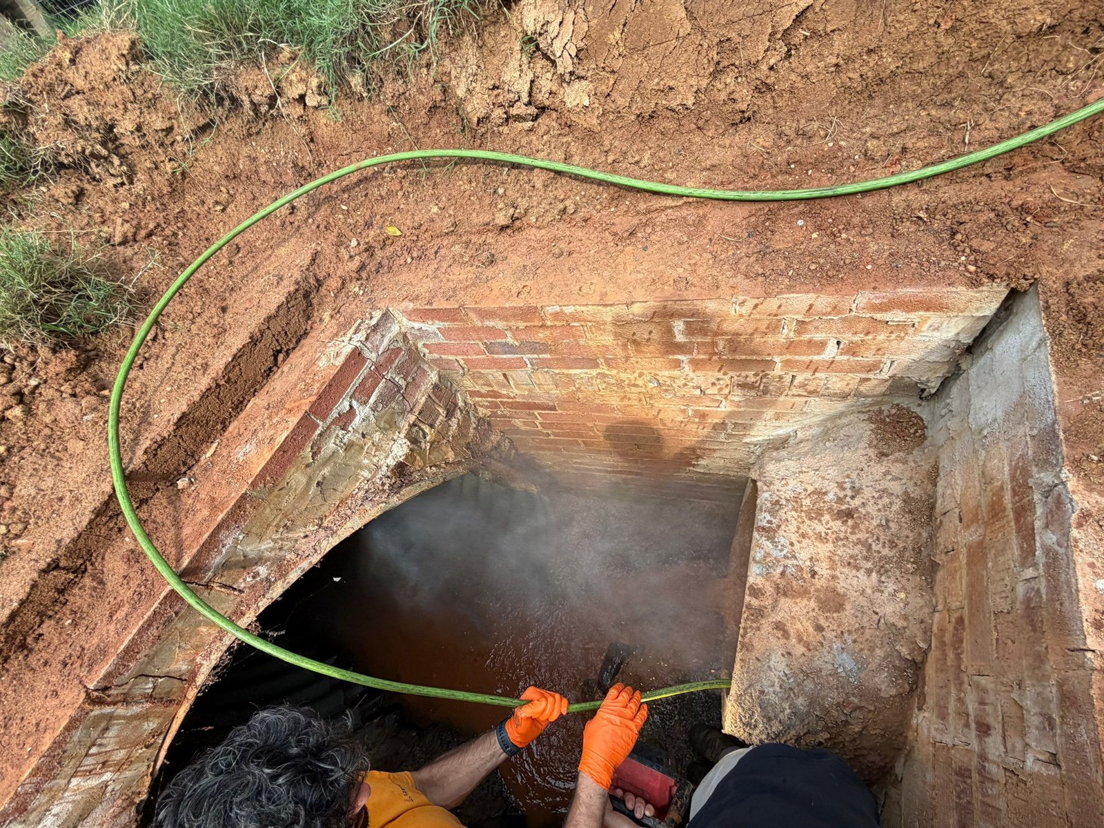 LiningWorks technician jetting the defect area of a storm drain culvert through an existing access point before spot liner installation.