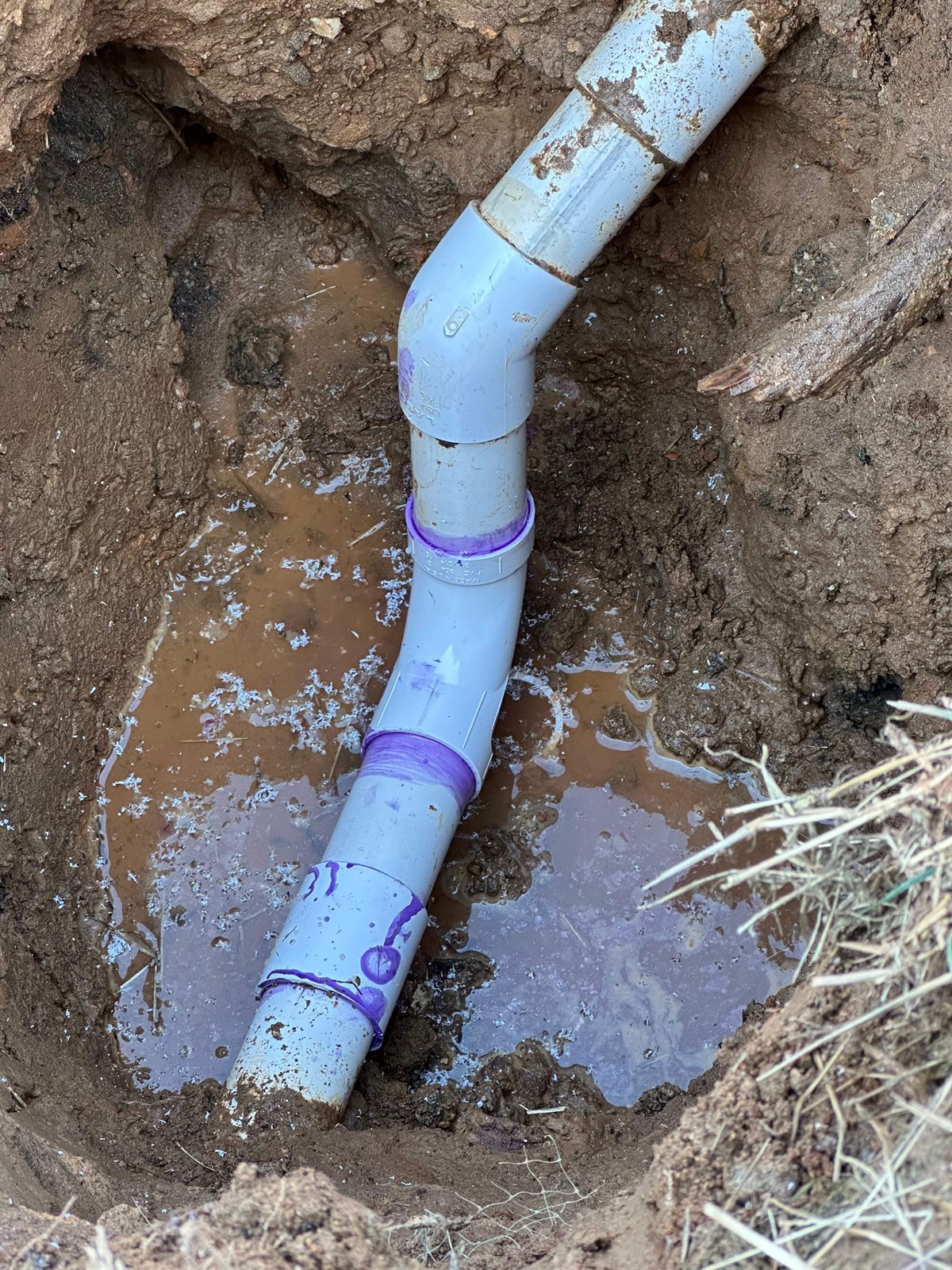 LiningWorks fitting new underground PVC sewer pipe in an excavated trench during a sewer line installation.